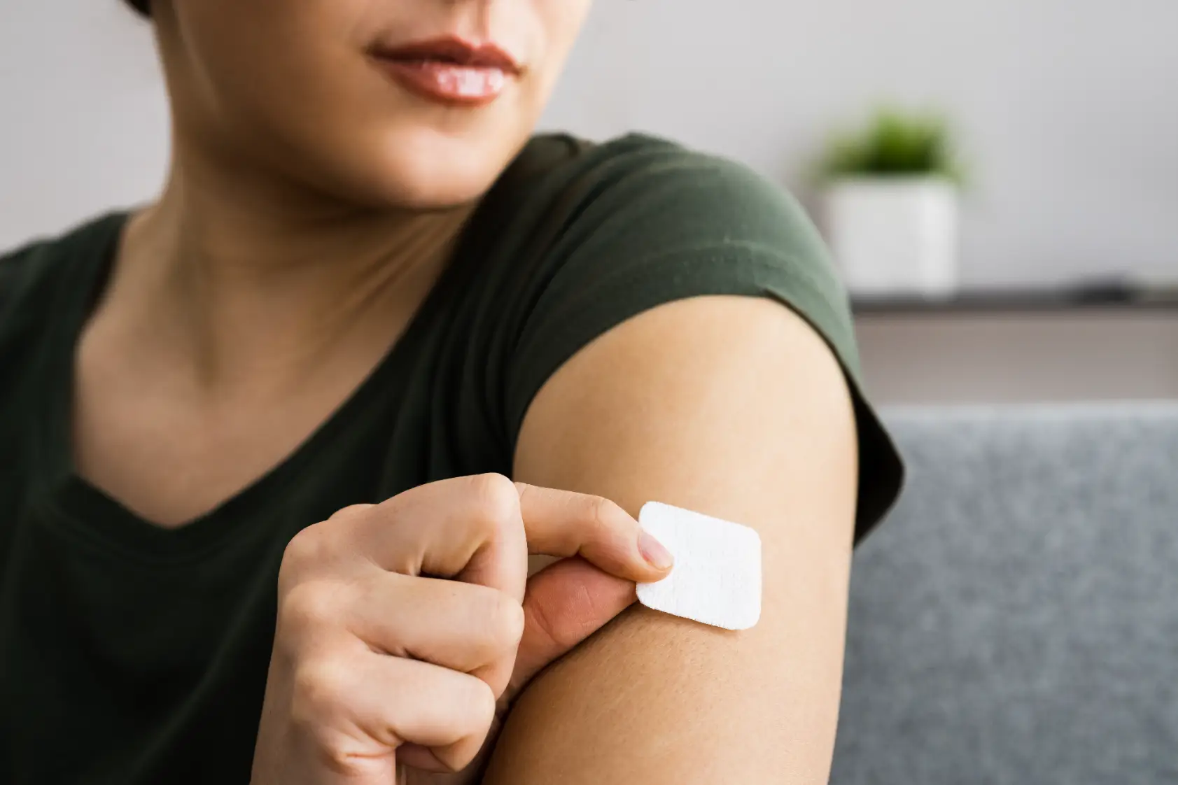 Person placing small patch on upper arm for hormone therapy