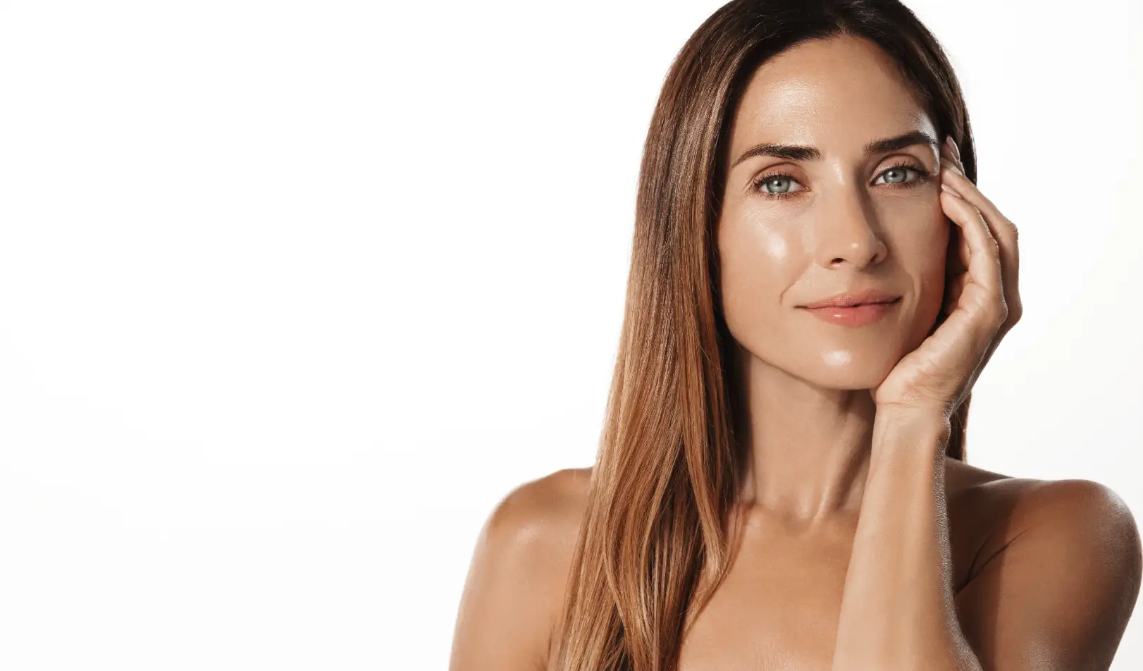 Woman with long hair resting one hand on her face against a light background.