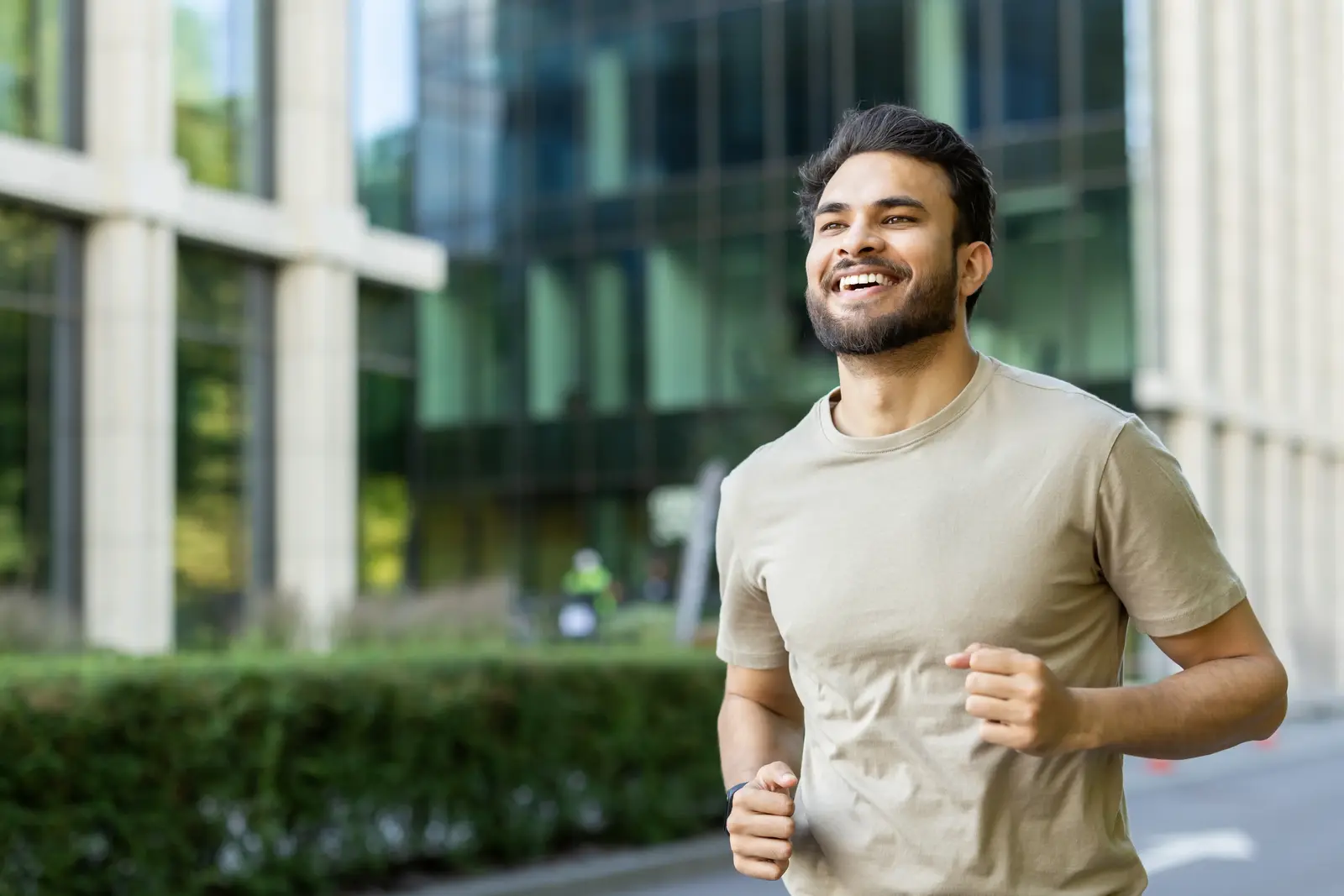 Man jogging outdoors near modern buildings on a sunny day.